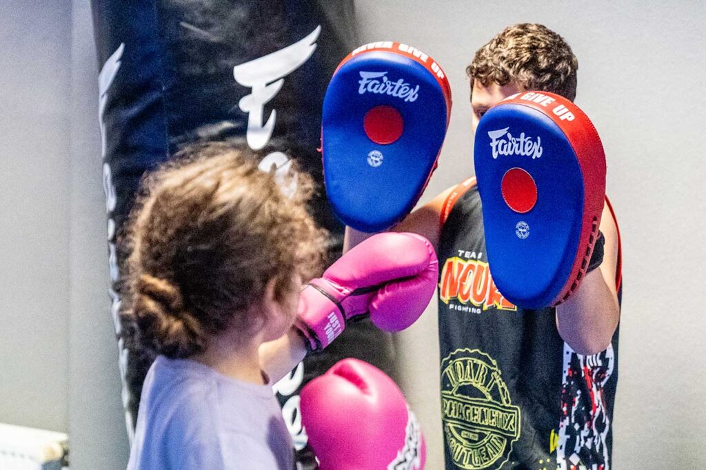 Kind übt eine Kicktechnik mit dem Trainer